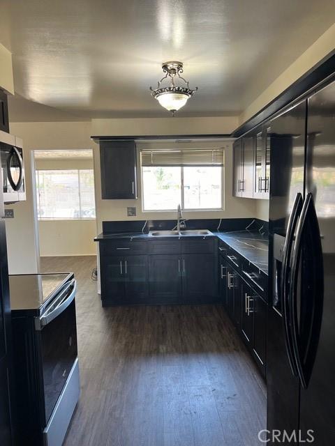 kitchen with electric stove, dark wood-type flooring, sink, and black fridge