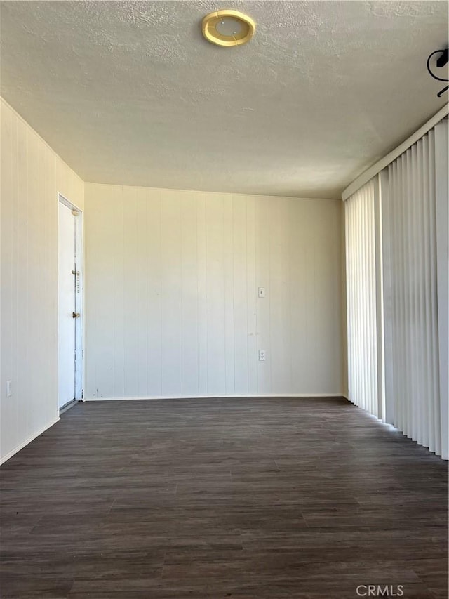 unfurnished room featuring dark wood-type flooring and a textured ceiling