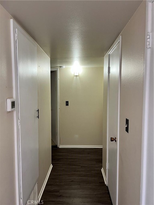 hallway featuring dark wood-type flooring and a textured ceiling