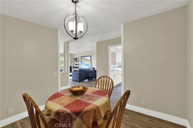 dining area featuring baseboards, dark wood finished floors, and a notable chandelier