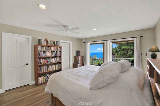 bedroom featuring a ceiling fan, dark wood-style floors, a water view, access to exterior, and recessed lighting