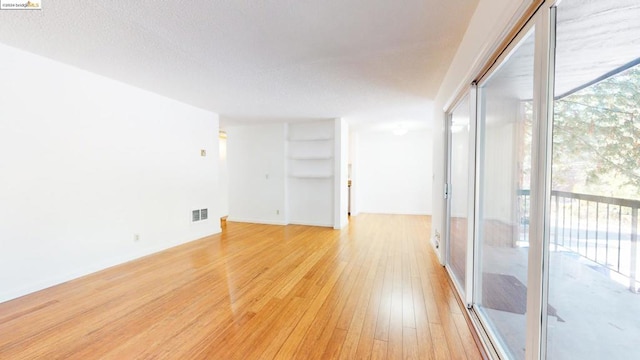 unfurnished room with light hardwood / wood-style floors, floor to ceiling windows, and plenty of natural light