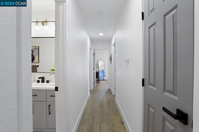 hall with light hardwood / wood-style floors and sink