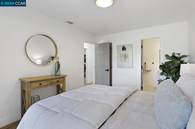 bedroom with ensuite bathroom and light wood-type flooring