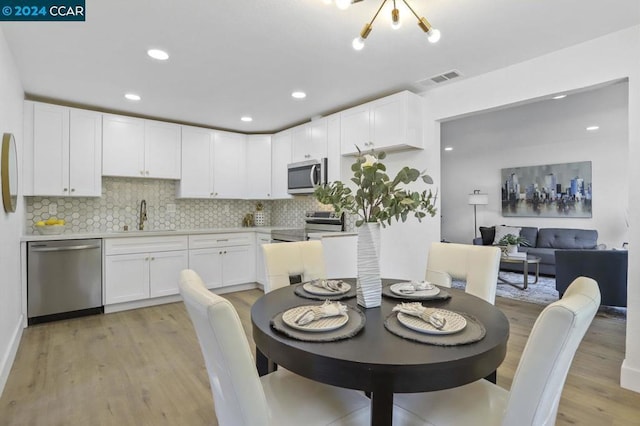 dining space featuring a notable chandelier, light hardwood / wood-style floors, and sink