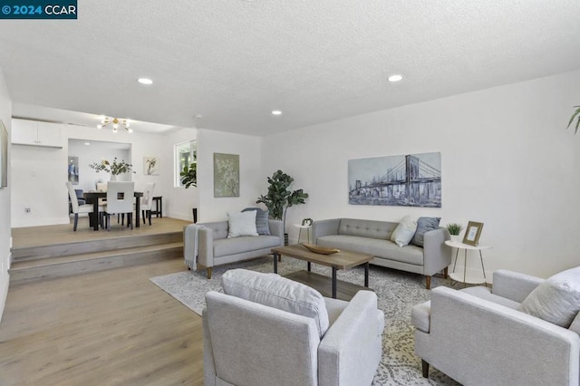 living room featuring a textured ceiling, light hardwood / wood-style floors, and a chandelier