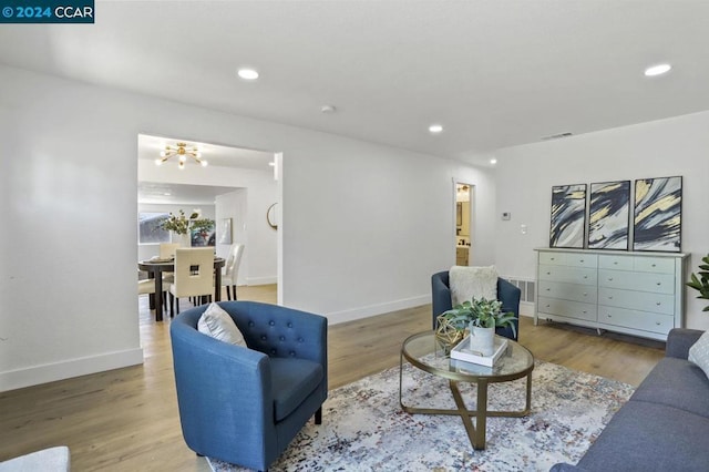 living room with light hardwood / wood-style flooring and an inviting chandelier