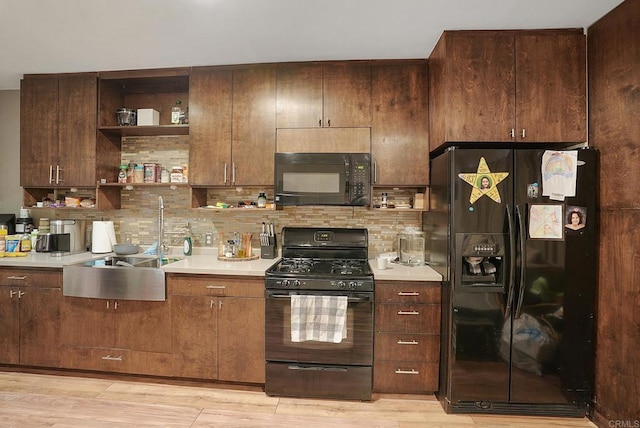 kitchen with decorative backsplash, sink, black appliances, and light hardwood / wood-style floors