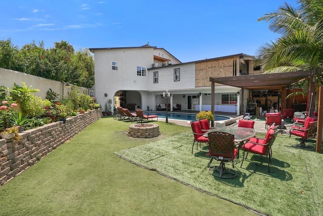 back of house featuring a pergola, a lawn, a fenced in pool, a fire pit, and a patio