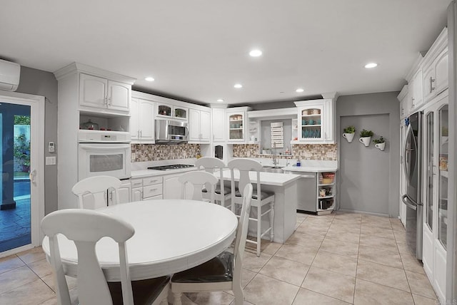 kitchen featuring decorative backsplash, appliances with stainless steel finishes, white cabinets, and light tile patterned floors