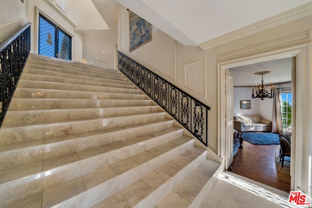 stairs with ornamental molding, hardwood / wood-style floors, and a chandelier