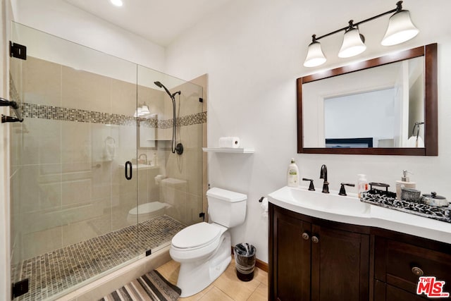 bathroom featuring a shower with door, vanity, toilet, and tile patterned flooring