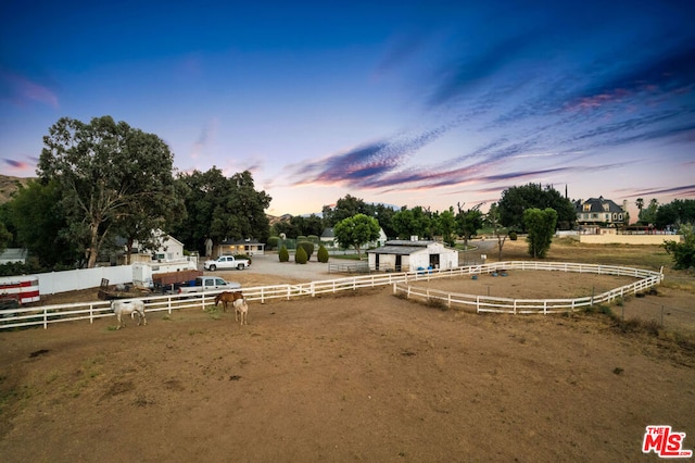 yard at dusk featuring a rural view