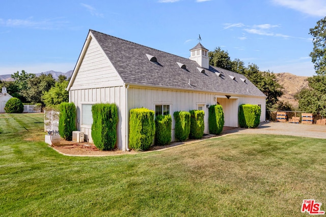 view of side of property with a garage, a mountain view, and a lawn