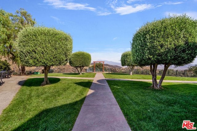 surrounding community with a mountain view and a lawn