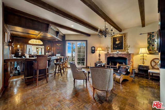 living room with wood walls, parquet floors, beam ceiling, a premium fireplace, and a chandelier