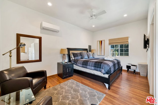 bedroom with ceiling fan, a wall mounted AC, and light wood-type flooring