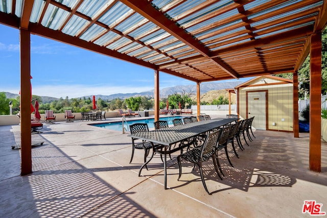 view of patio / terrace with a shed, a mountain view, a community pool, and a pergola