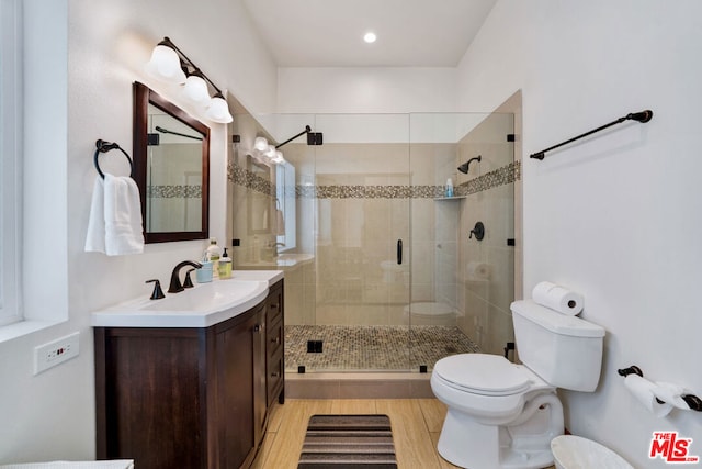 bathroom with vanity, toilet, hardwood / wood-style flooring, and a shower with shower door