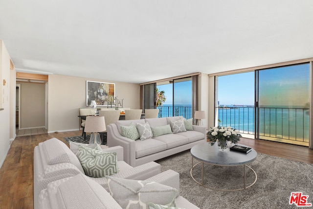 living room with floor to ceiling windows, wood-type flooring, and a water view