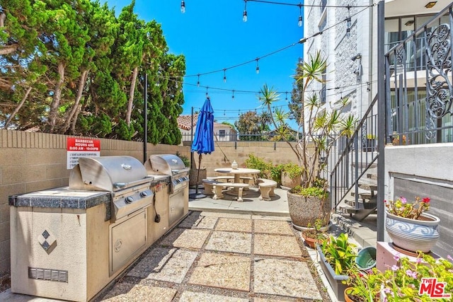 view of patio with exterior kitchen and a grill