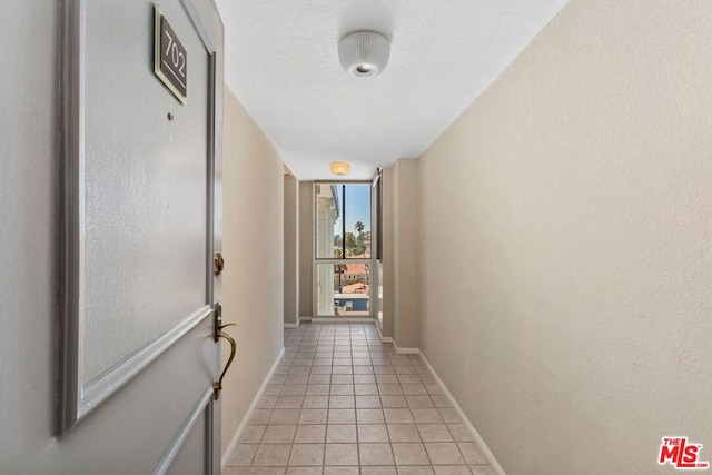 corridor with a wall of windows and light tile patterned floors