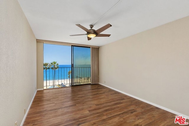 spare room featuring a water view, floor to ceiling windows, ceiling fan, and dark hardwood / wood-style flooring