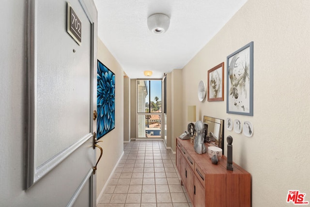 corridor with a wall of windows and light tile patterned floors