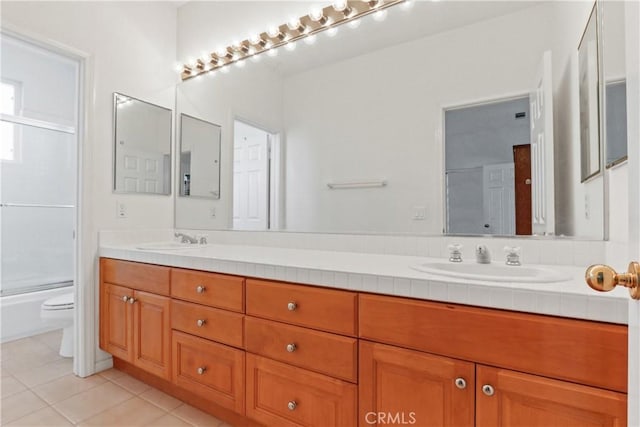 bathroom featuring a sink, toilet, double vanity, and tile patterned floors