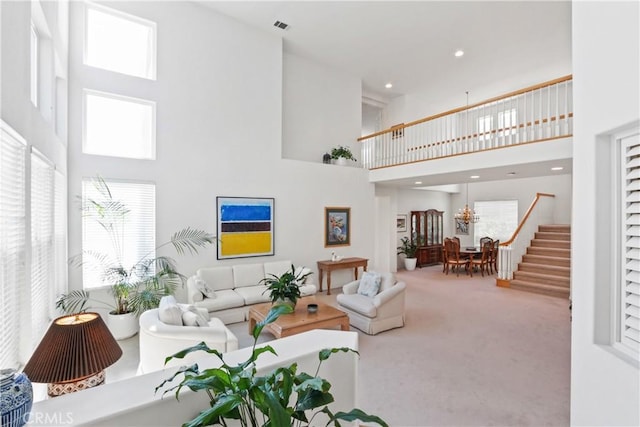 carpeted living room featuring visible vents, stairs, and a high ceiling