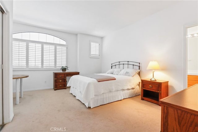 carpeted bedroom featuring baseboards and ensuite bathroom