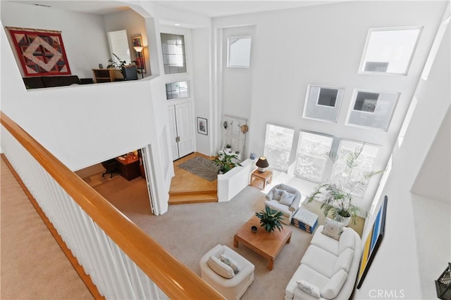 carpeted living area with plenty of natural light and a towering ceiling