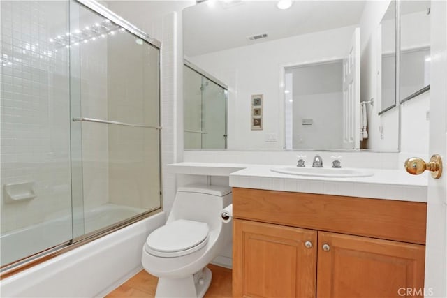 bathroom with vanity, toilet, visible vents, and shower / bath combination with glass door