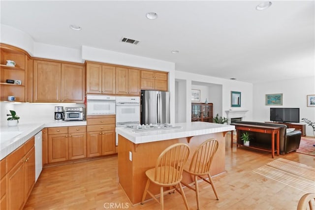 kitchen with visible vents, a kitchen island, a breakfast bar, white appliances, and open shelves