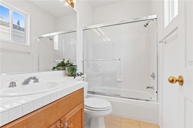 bathroom featuring combined bath / shower with glass door, toilet, vanity, and tile patterned flooring