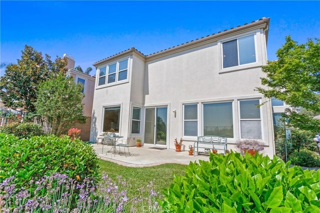 back of house featuring stucco siding, a patio, a lawn, and fence