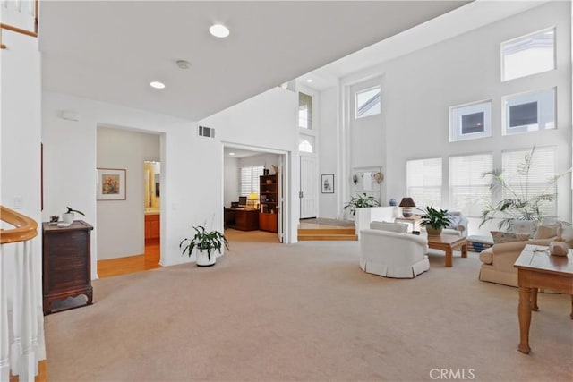 living area featuring carpet flooring, recessed lighting, a high ceiling, and visible vents