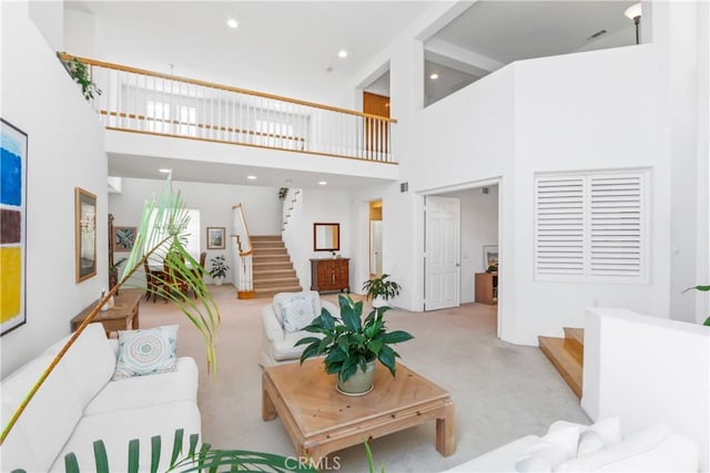 living room with stairway, a towering ceiling, and carpet floors