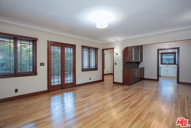 unfurnished living room featuring french doors, light hardwood / wood-style flooring, and sink