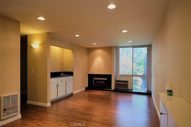 3601 W Hidden Ln Unit 121, Rolling Hills Estates, CA 90274 - unfurnished living room featuring dark wood-style flooring, a fireplace with raised hearth, recessed lighting, expansive windows, and a wall mounted air conditioner