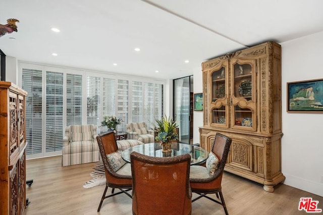 dining area with floor to ceiling windows and light hardwood / wood-style flooring