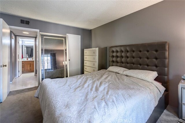 carpeted bedroom with a textured ceiling and a closet