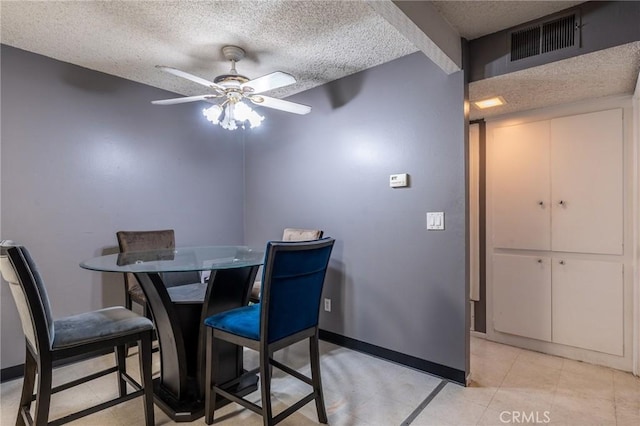 tiled dining area with a textured ceiling and ceiling fan