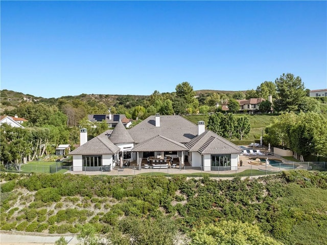 rear view of property featuring a patio, a tiled roof, a fenced backyard, and a chimney