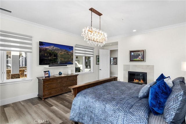 bedroom with visible vents, wood finished floors, a high end fireplace, crown molding, and baseboards