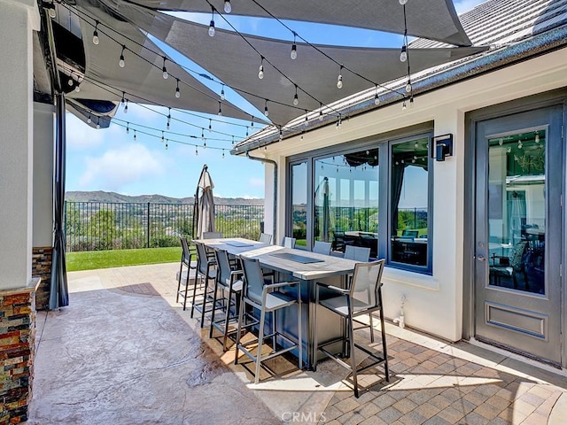 view of patio featuring a mountain view, outdoor dining space, and fence