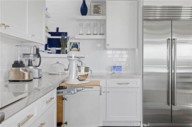 kitchen featuring open shelves, built in refrigerator, tasteful backsplash, and white cabinetry