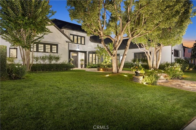 view of front of house with stucco siding and a front lawn