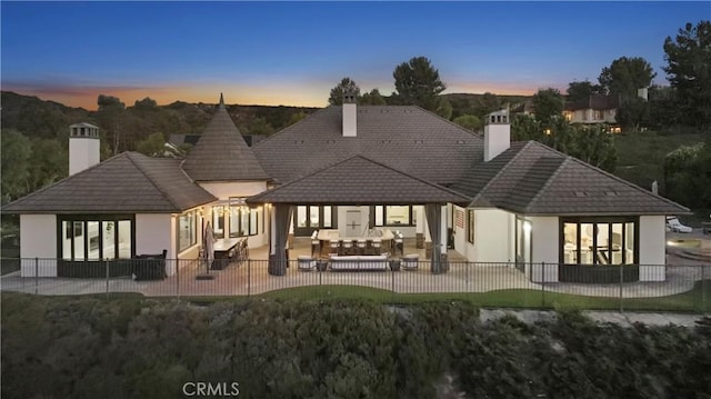 back of property featuring a patio, stucco siding, fence, and a chimney