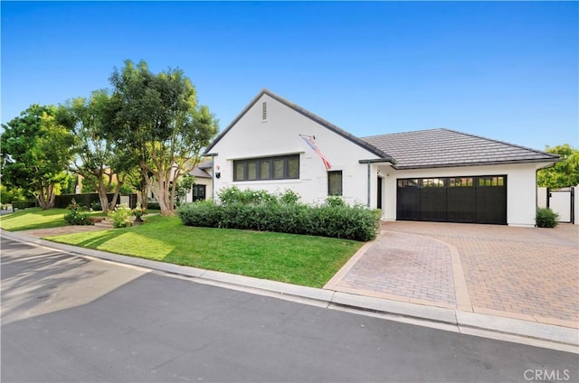 view of front of property with stucco siding, a front lawn, decorative driveway, and a garage